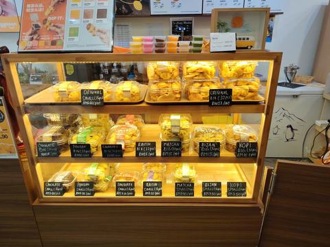 A lit display counter with tubs of baked goods and blackboard labels