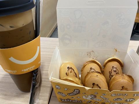 A drink in an Eggteen cup beside a box of egg cakes