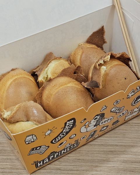 Golden egg cakes with crisp, lacy edges in a printed paper box