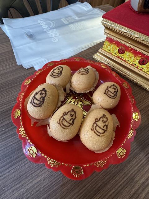 Seven egg cakes, each stamped with a cartoon face, on a red plate